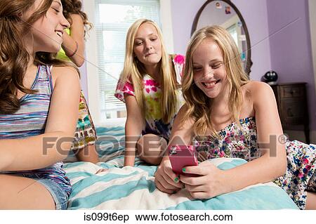 Stock Photography - Girls using smartphone in bedroom. Fotosearch