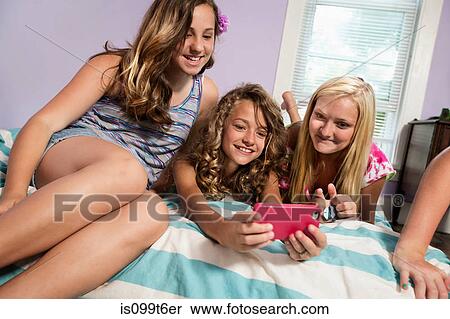 Stock Photography - Girls using smartphone in bedroom. Fotosearch
