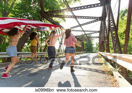 Group of friends running on bridge holding american flag View Large Photo Image Picture - Group of friends running on bridge holding american flag. Fotosearch