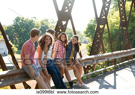 Group of friends sitting on bridge View Large Photo Image Stock Image - Group of friends sitting on bridge. Fotosearch