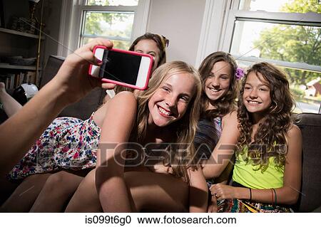 Stock Image - Group of girls being photographed with camera phone. Fotosearch