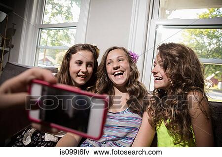 Stock Photo - Group of girls being photographed with camera phone. Fotosearch