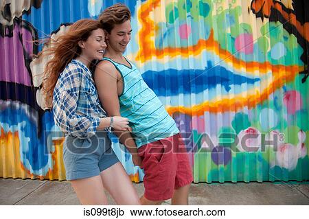 Stock Image - Man leaning on woman in front of graffiti. Fotosearch