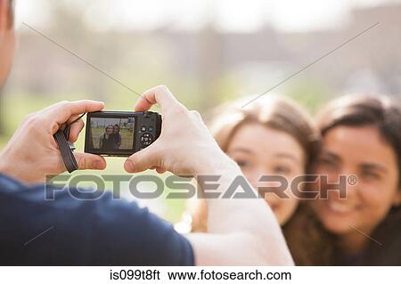 Man taking a photograph of two young women View Large Photo Image Stock Photograph - Man taking a photograph of two young women. Fotosearch