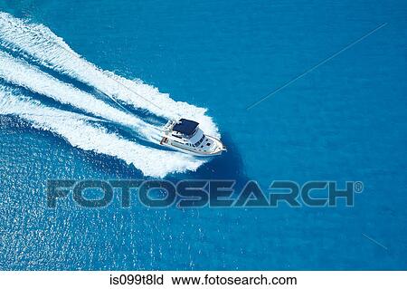 Stock Image - Motor yacht ploughing across blue sea. Fotosearch