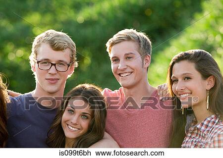 Stock Image - Portrait of four friends with arms around each other. Fotosearch