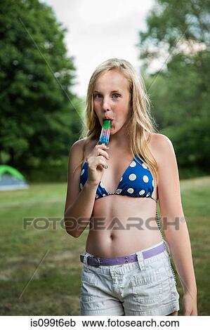 Stock Image - Portrait of girl eating ice lolly. Fotosearch