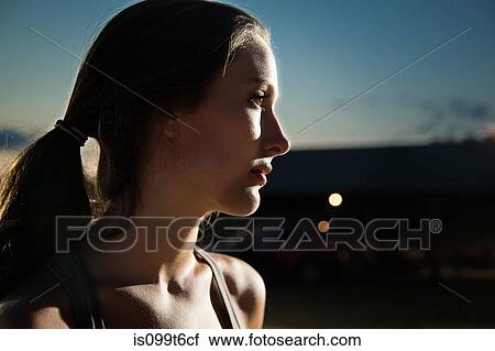 Stock Image - Portrait of girl looking away, at night. Fotosearch