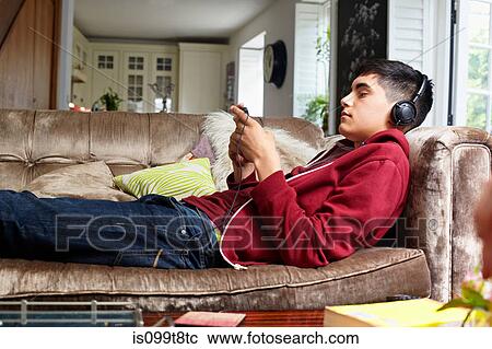 Teenage boy on sofa, listening to music View Large Photo Image Stock Image - Teenage boy on sofa, listening to music. Fotosearch