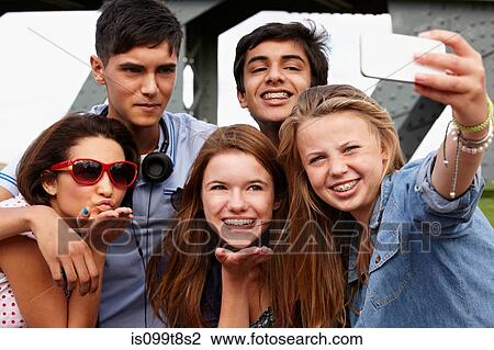 Stock Image - Teenage friends photographing themselves with smartphone. Fotosearch