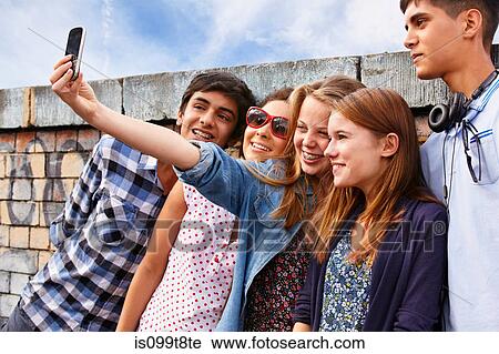 Stock Image - Teenage friends photographing themselves with smartphone. Fotosearch