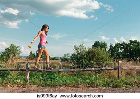 Stock Photo - Teenage girl balancing on wooden fence. Fotosearch