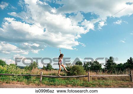 Stock Photo - Teenage girl balancing on wooden fence. Fotosearch