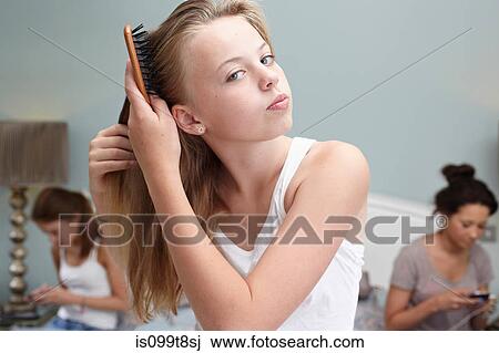 Stock Image - Teenage girl brushing her hair. Fotosearch