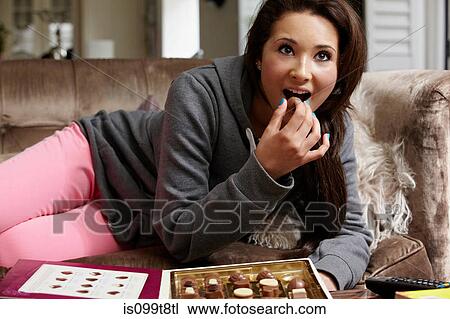 Teenage girl eating chocolates on sofa View Large Photo Image Stock Image - Teenage girl eating chocolates on sofa. Fotosearch