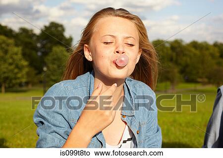 Teenage girl in park, blowing bubble gum View Large Photo Image Picture - Teenage girl in park, blowing bubble gum. Fotosearch