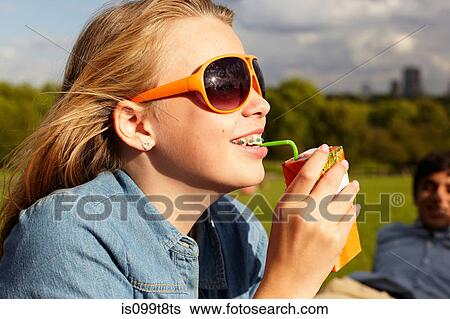 Stock Photograph - Teenage girl in sunglasses drinking from juice carton. Fotosearch
