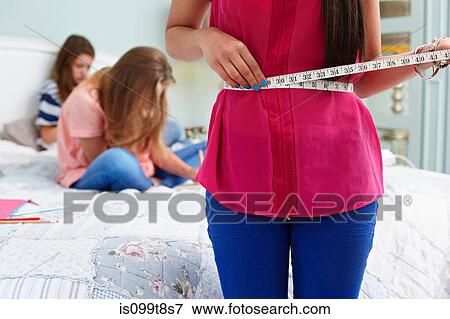 Teenage girl measuring her waist View Large Photo Image Stock Photo - Teenage girl measuring her waist. Fotosearch