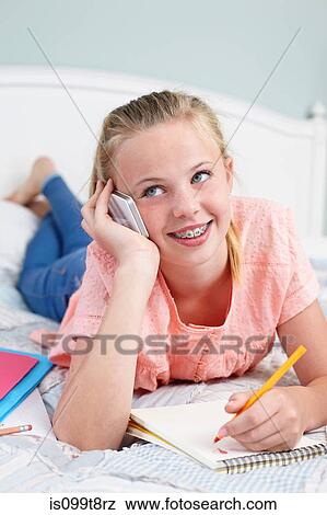 Stock Photo - Teenage girl on cellphone with notepad. Fotosearch