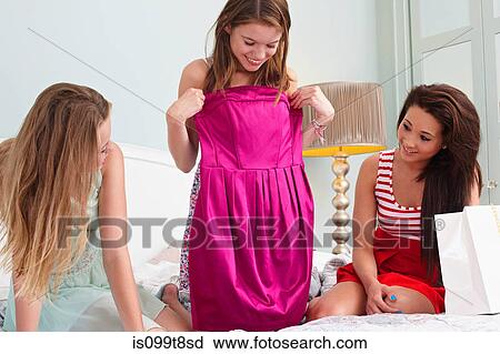 Stock Image - Teenage girl showing dress to friends. Fotosearch