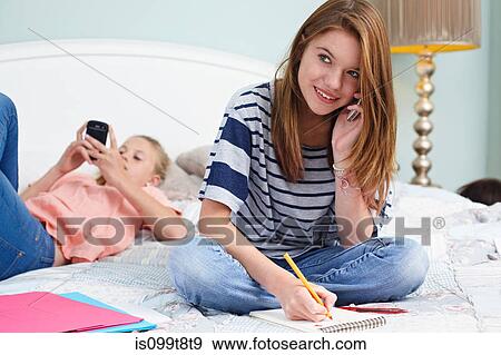 Teenage girl sitting on bed, using cellphone View Large Photo Image Stock Photo - Teenage girl sitting on bed, using cellphone. Fotosearch