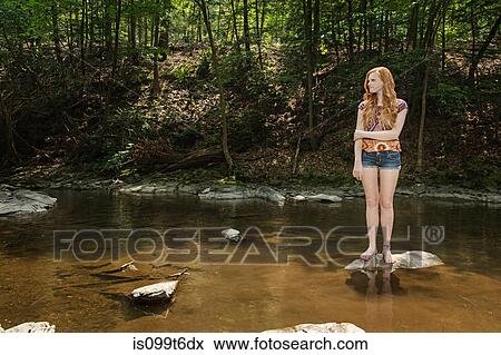 Teenage girl standing on rock in river View Large Photo Image Stock Photo - Teenage girl standing on rock in river. Fotosearch