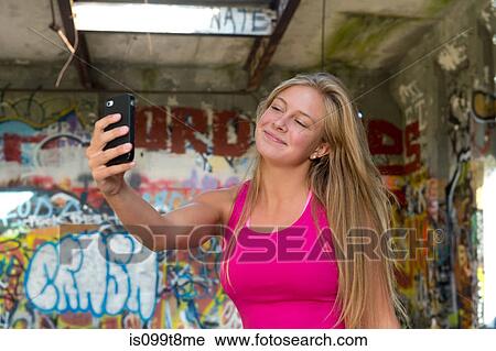 Stock Image - Teenage girl taking a picture of herself on smartphone. Fotosearch
