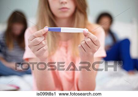 Stock Image - Teenage girl with pregnancy test. Fotosearch