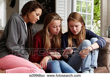 Teenage girls looking at a cellphone View Large Photo Image Picture - Teenage girls looking at a cellphone. Fotosearch