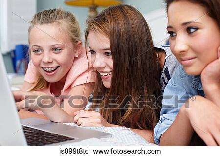 Teenage girls looking at laptop View Large Photo Image Stock Image - Teenage girls looking at laptop. Fotosearch