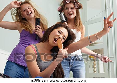 Teenage girls singing into hairbrushes View Large Photo Image Picture - Teenage girls singing into hairbrushes. Fotosearch