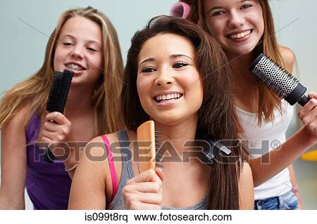 Teenage girls singing into hairbrushes View Large Photo Image Stock Photography - Teenage girls singing into hairbrushes. Fotosearch