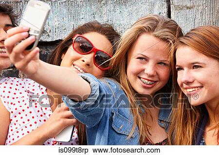 Stock Photography - Teenage girls taking a picture of themselves on smartphone. Fotosearch