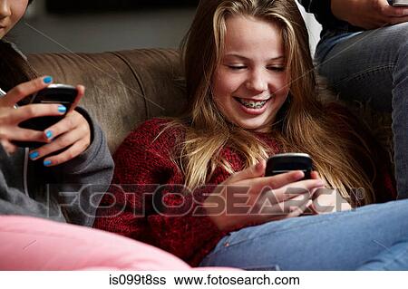 Stock Photograph - Teenage girls using smartphones. Fotosearch