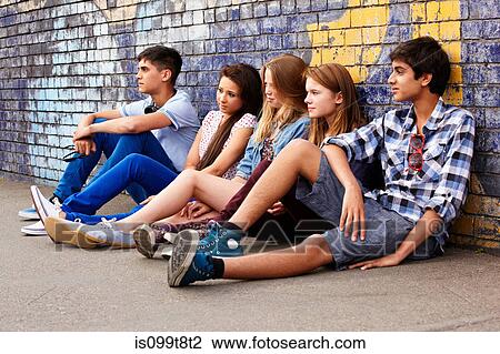 Stock Image - Teenagers sitting against a wall. Fotosearch