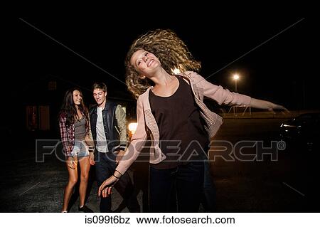 Stock Photo - Three friends in parking lot at night. Fotosearch