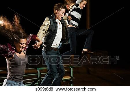 Three friends jumping over bleachers at night View Large Photo Image Stock Photo - Three friends jumping over bleachers at night. Fotosearch