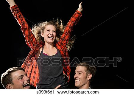 Stock Image - Two male friends lifting teenage girl, arms outstretched. Fotosearch