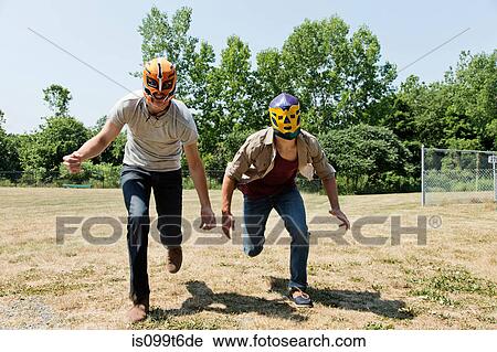 Stock Image - Two young men wearing wrestling masks. Fotosearch