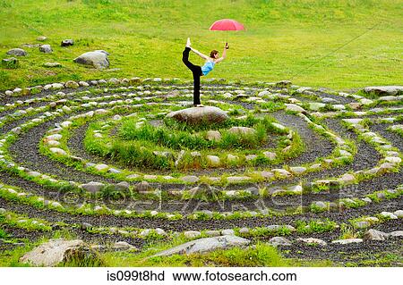 Woman holding an umbrella whilst in yoga pose in centre of stone maze View Large Photo Image Stock Image - Woman holding an umbrella whilst in yoga pose in centre of stone maze. Fotosearch