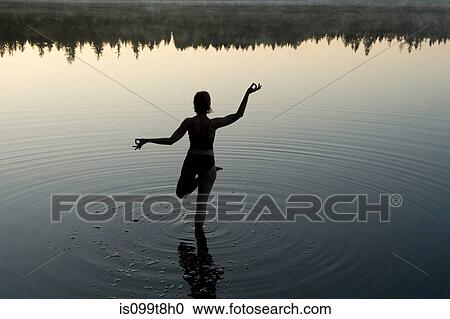Stock Image - Woman in yoga pose in lake. Fotosearch
