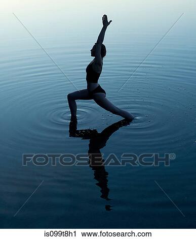 Stock Image - Woman in yoga pose in lake. Fotosearch