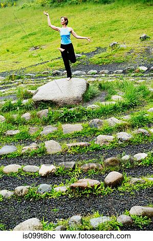 Woman in yoga pose on stone in maze View Large Photo Image Stock Image - Woman in yoga pose on stone in maze. Fotosearch