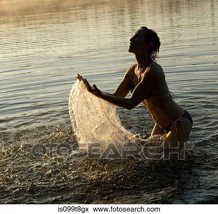 Stock Photo - Woman splashing in water of lake. Fotosearch