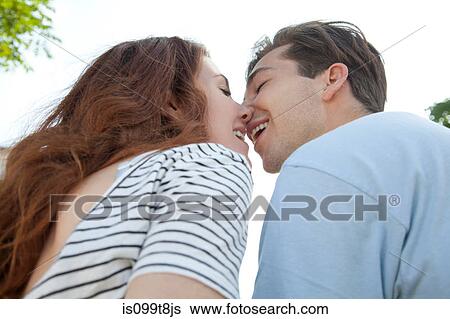 Stock Photograph - Young couple kissing, low angle. Fotosearch