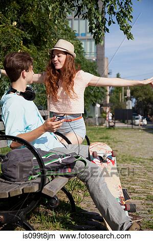 Picture - Young couple on bench listening to music. Fotosearch