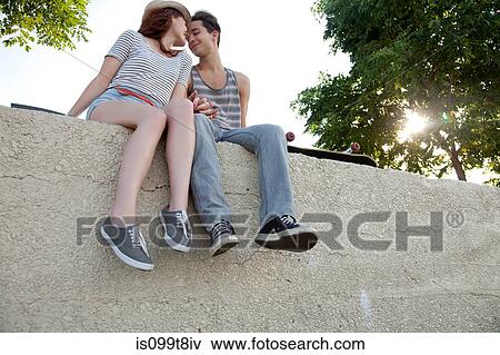 Young couple sitting on wall holding hands View Large Photo Image Stock Photo - Young couple sitting on wall holding hands. Fotosearch
