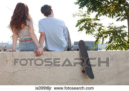 Young couple sitting on wall holding hands View Large Photo Image Stock Photography - Young couple sitting on wall holding hands. Fotosearch