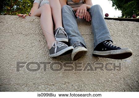 Young couple sitting on wall, low section View Large Photo Image Stock Photograph - Young couple sitting on wall, low section. Fotosearch