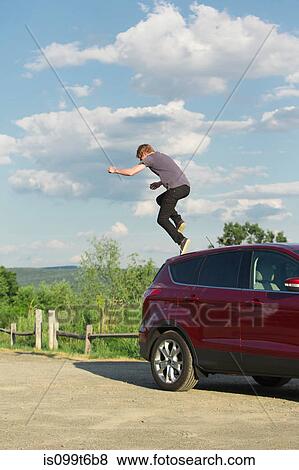 Stock Photo - Young man jumping off car. Fotosearch